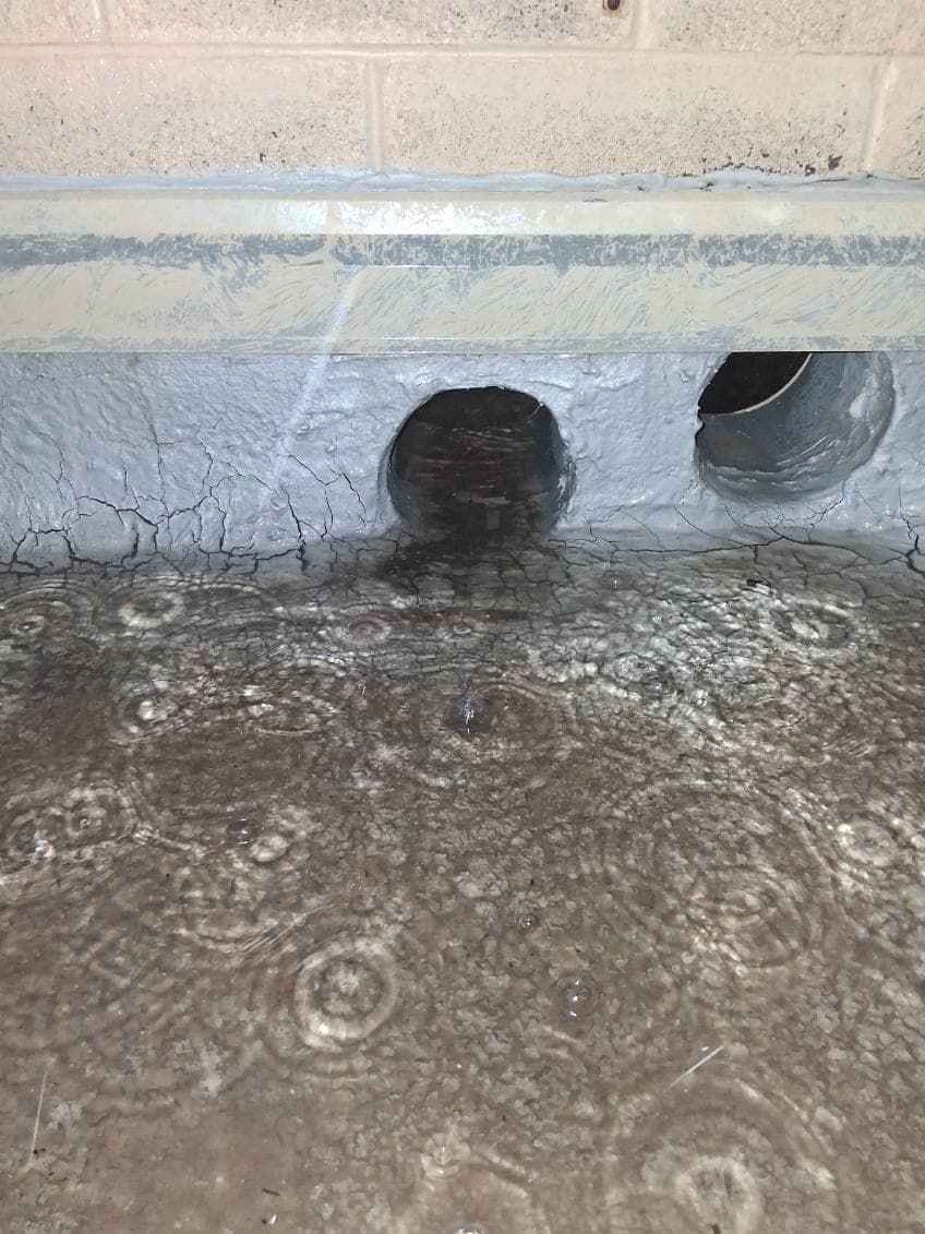 Rainwater ponding in front of two clogged roof scupper openings at night