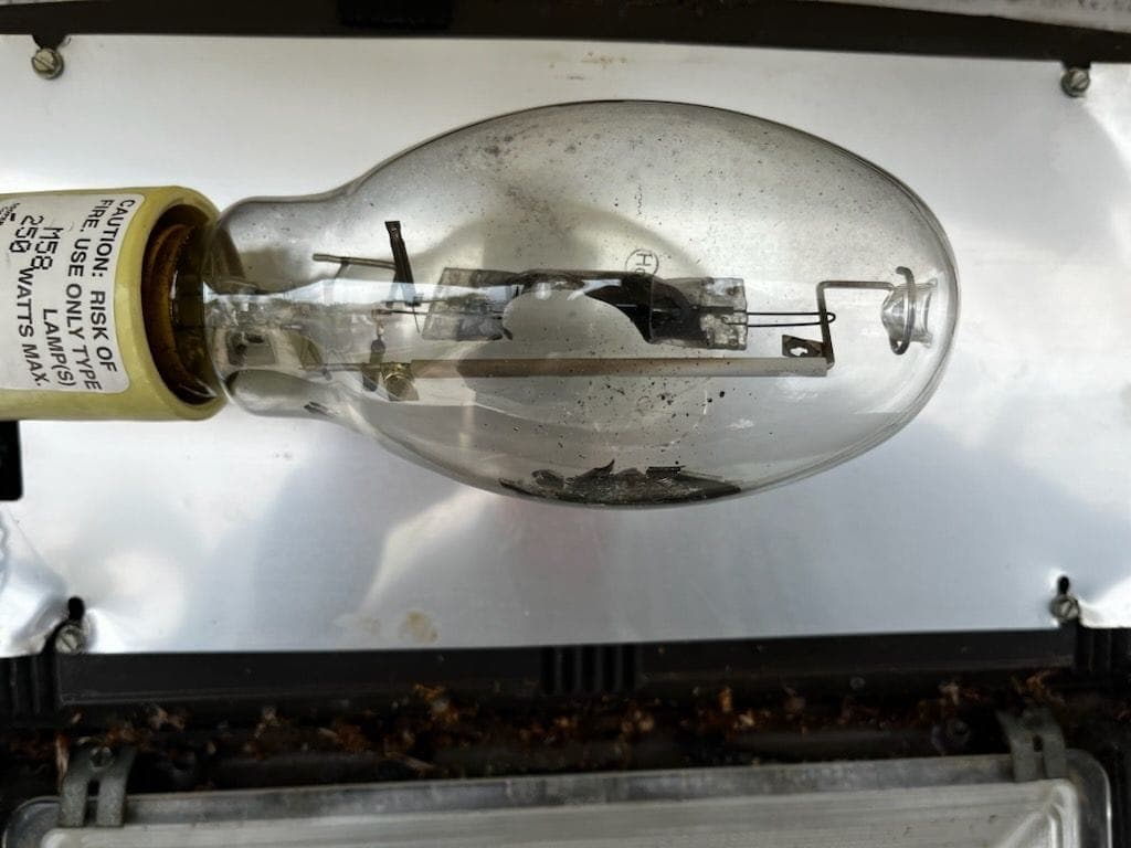 Burned-out metal halide lamp with a shattered arc tube inside a wall light
