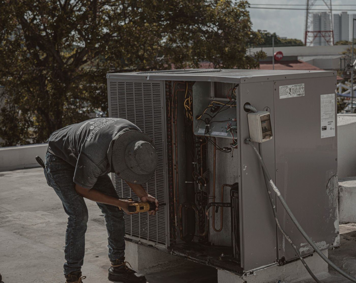 Technician testing the electrical panel of a rooftop air conditioning unit