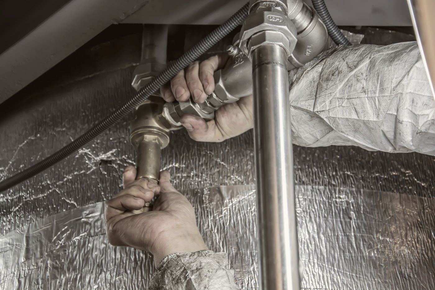 Plumber tightening a pipe fitting with two wrenches