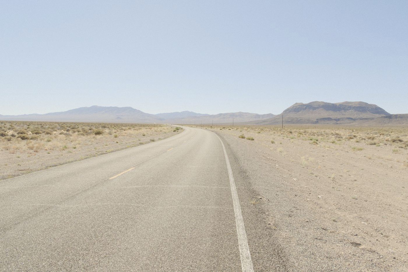 Empty two-lane highway crossing the Nevada desert toward mountains