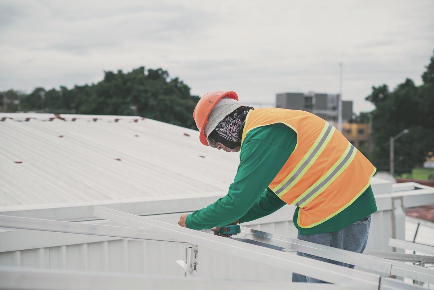 Worker in a hard hat and safety vest installing roof rails